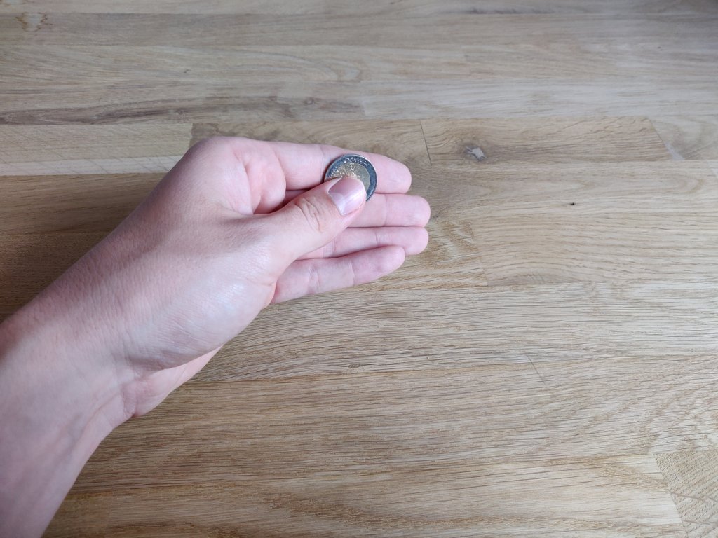 Die rechte Hand zeigst du leer vor, mit der linken Hand lässt du die Münze hinter einem Ohr erscheinen.